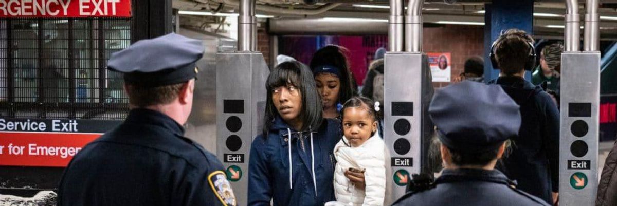 woman and child crossing subway turnstile with two police officers in front of them