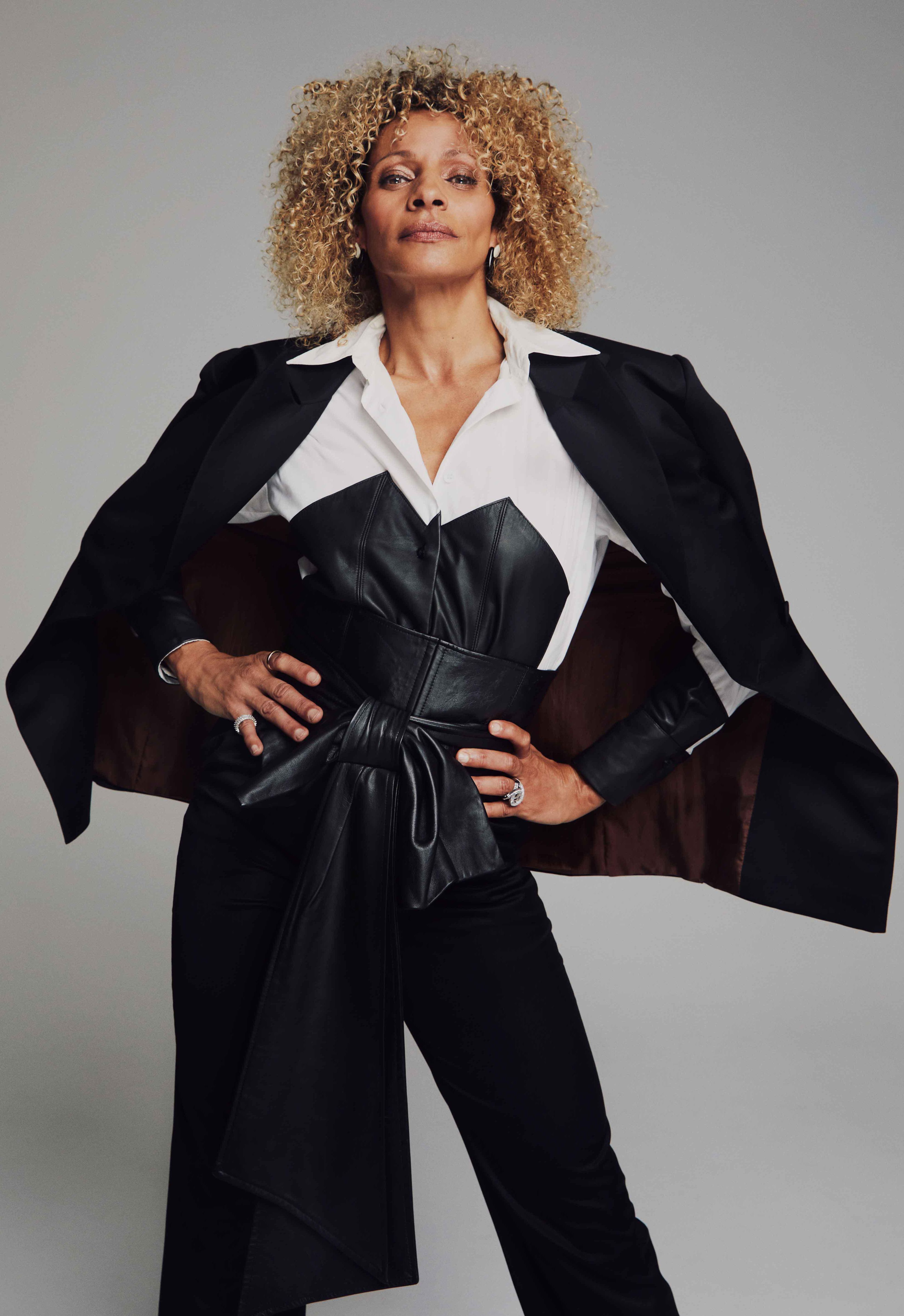 Star Trek Picard Actress Michelle Hurd wears a white shirt with a cloak and a leather vest.