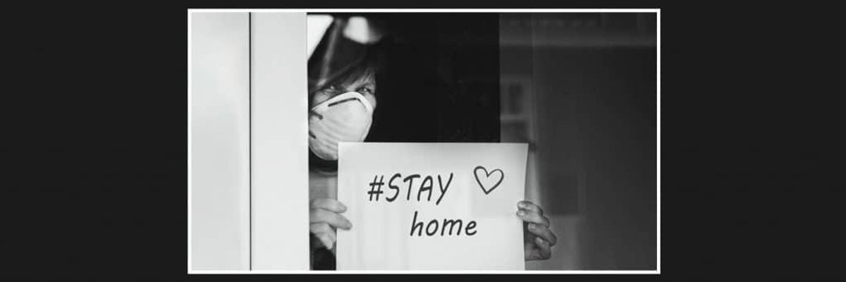 Woman with a mask holding sign that says "#Stay Home".