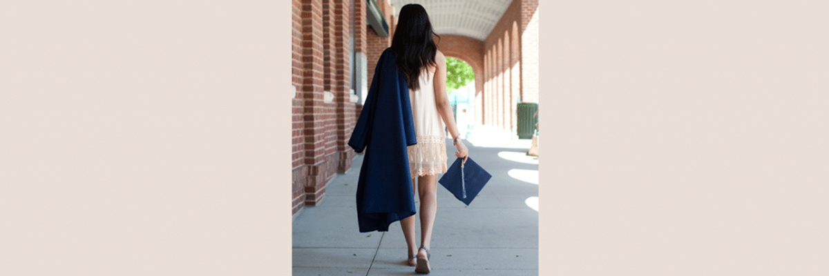 College graduate walking with her cap and gown.