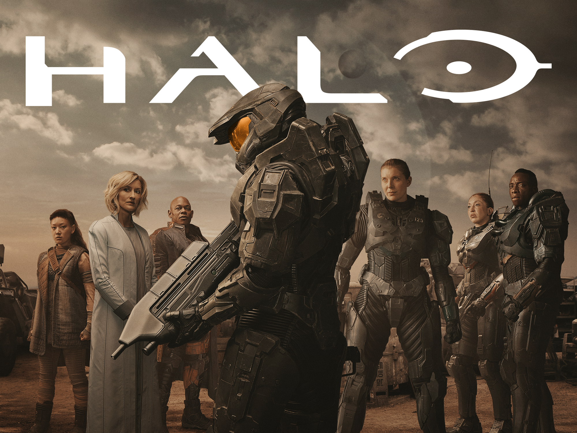 A promotional poster for Halo Season 1 shows Pablo Schreiber as Master Chief in uniform holding an MA5C assault rifle and surrounded by fellow cast members.