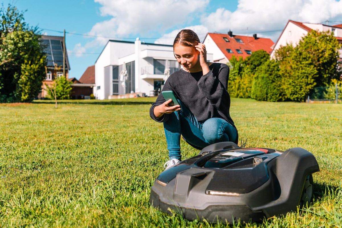 Photo of a woman testing a robotic lawn mower