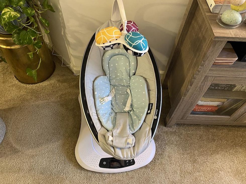 Photo of mamaroo4 Smart Swing in a living room with baby inserts.