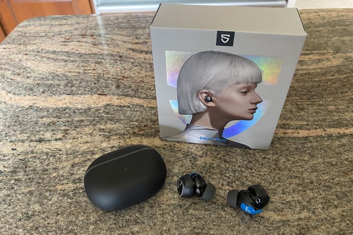 A photo of Soundpeats Mini Pro earbuds unboxed on a countertop