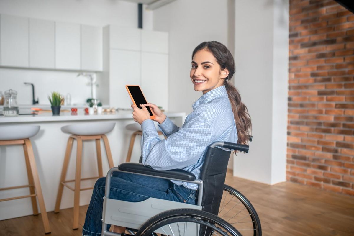 a woman in a wheel chair on her tablet in a kitchen