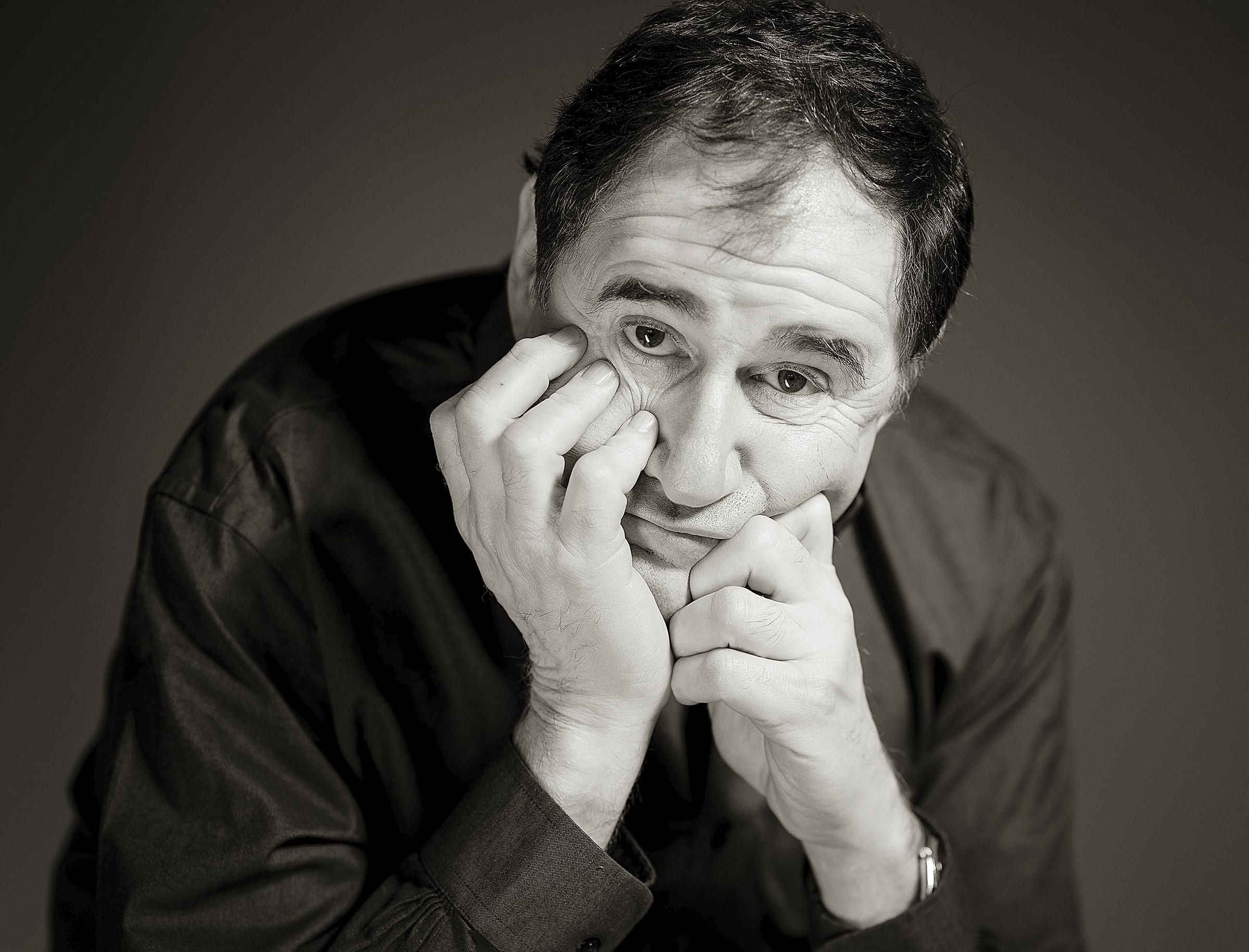 Actor Richard Kind poses with his chin in his hands looking pensive and comical.