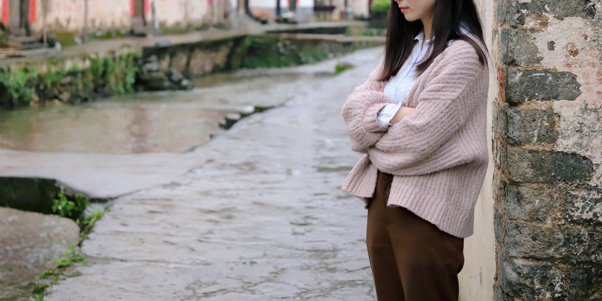 woman leaning on beige concrete wall