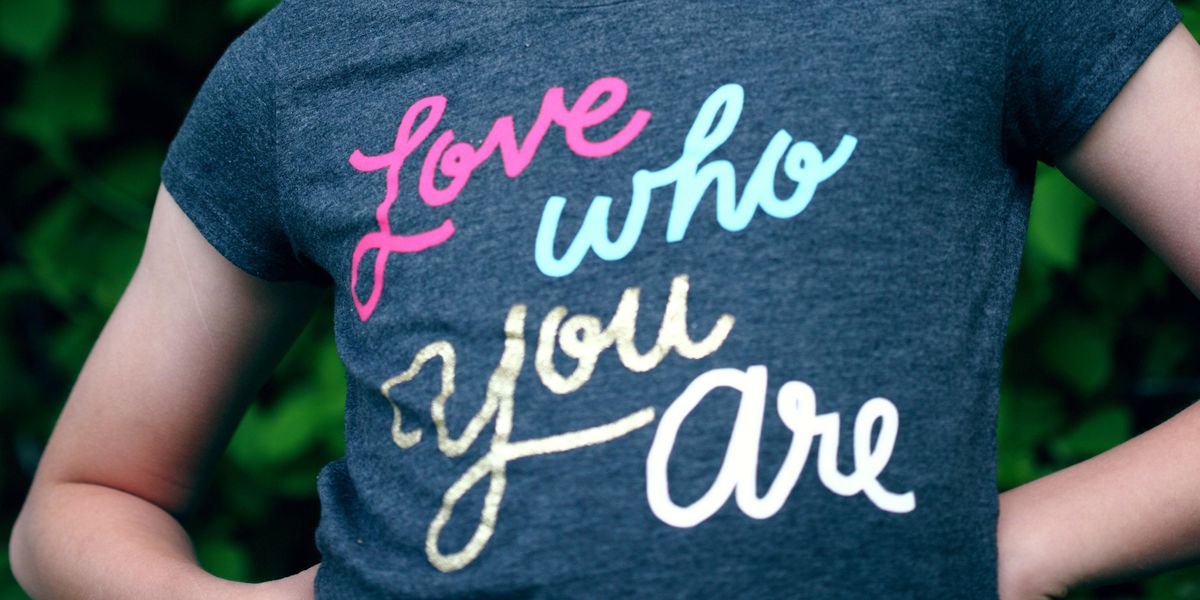 close-up of child's blue shirt with "Love who you are" written on it