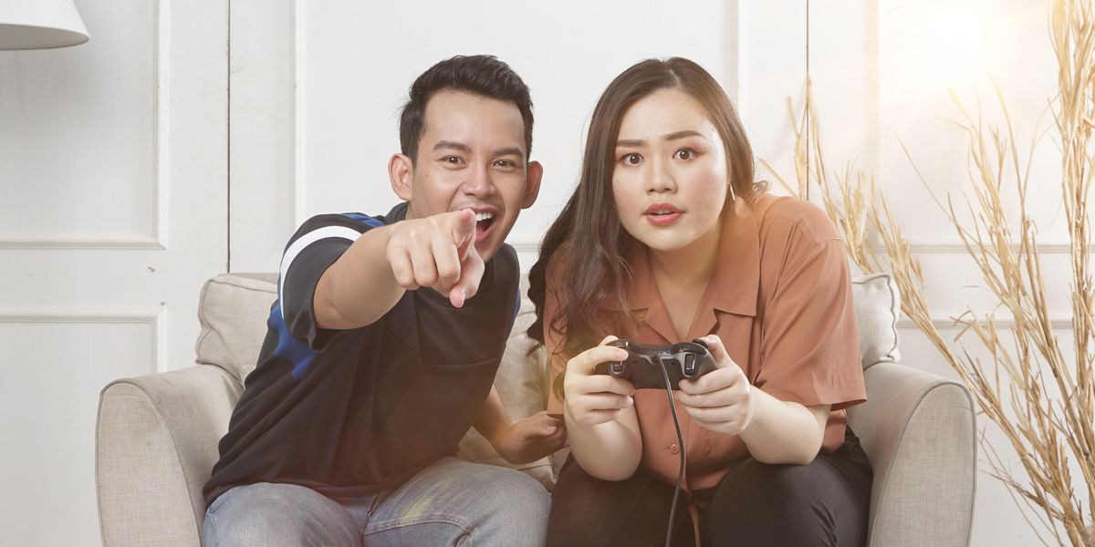 man and woman siting on loveseat playing video game
