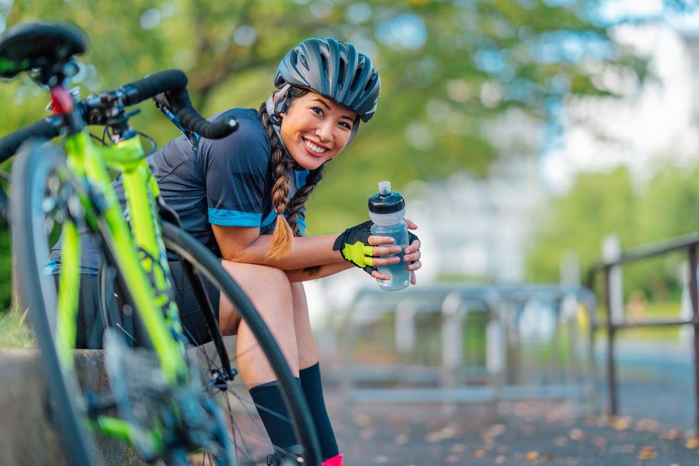 Photo of a female biker taking a break and drinking water from a water bottle