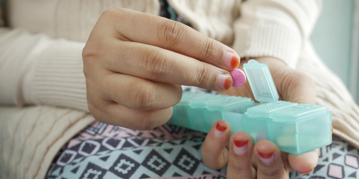 person holding medication organizer and pill