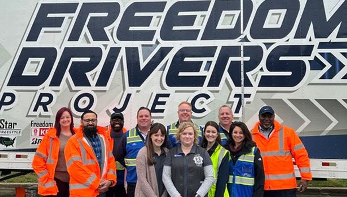Leaders from Penske Logistics pose with Truckers Against Trafficking associates outside of the Freedom Driver Project Trailer. 