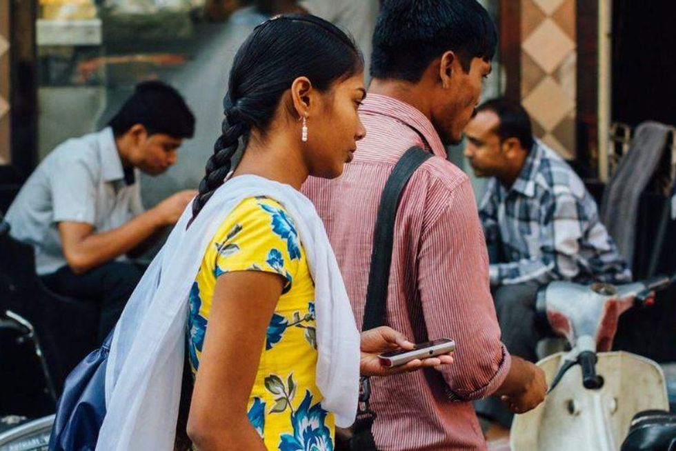 Indian woman walking through a market holding her cellphone
