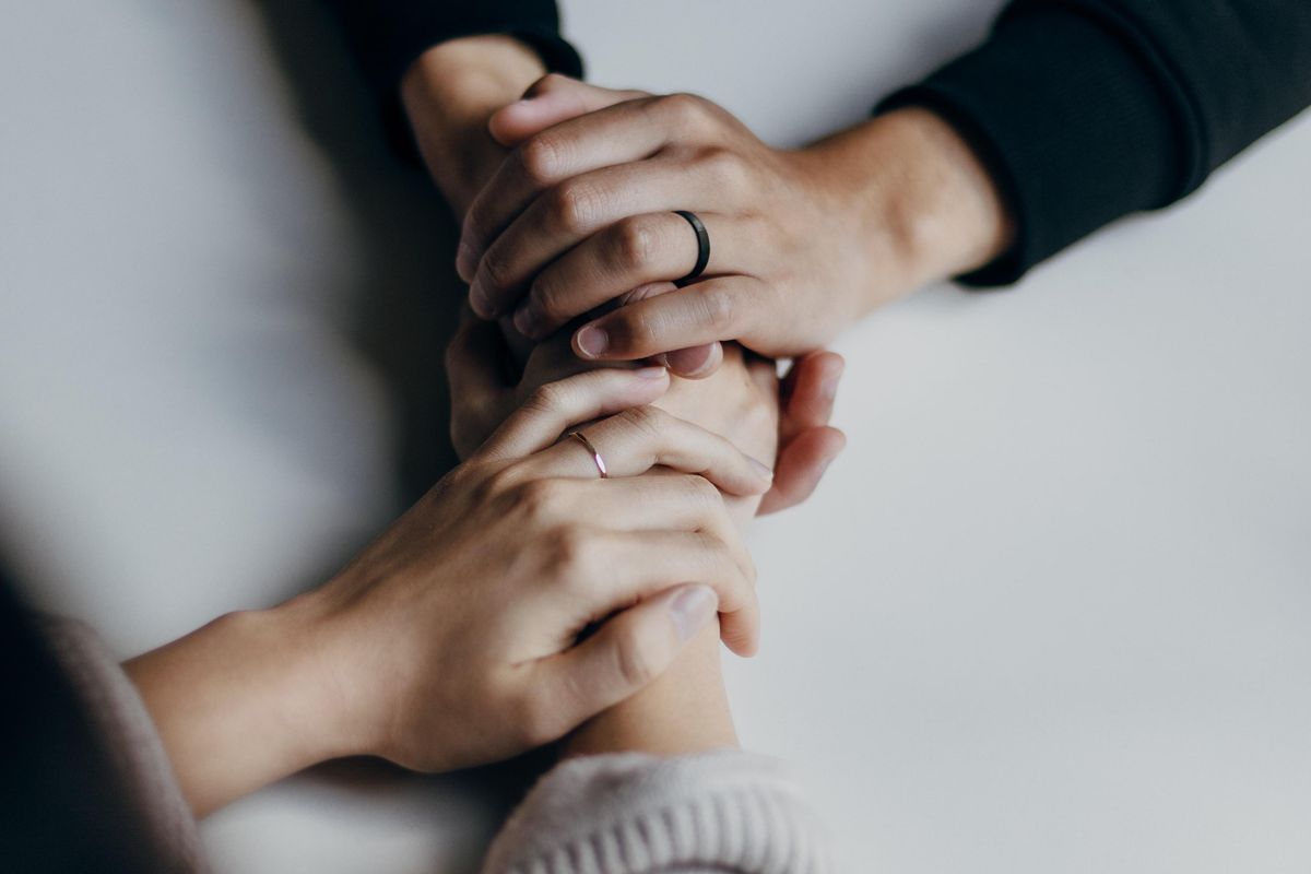 person in black long sleeve shirt holding hands with person in long cream colored sleeves