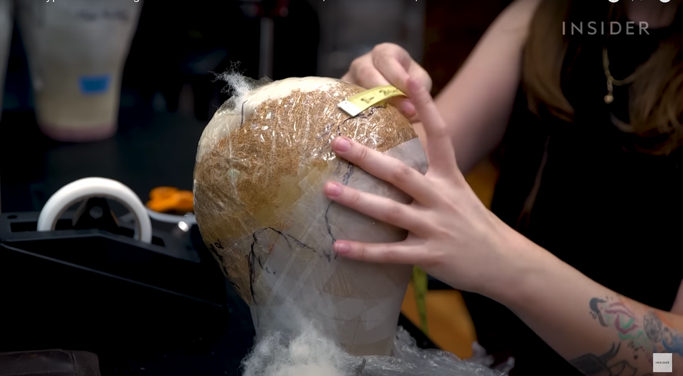 wigmaker's hands on a mold of an actor's skull.