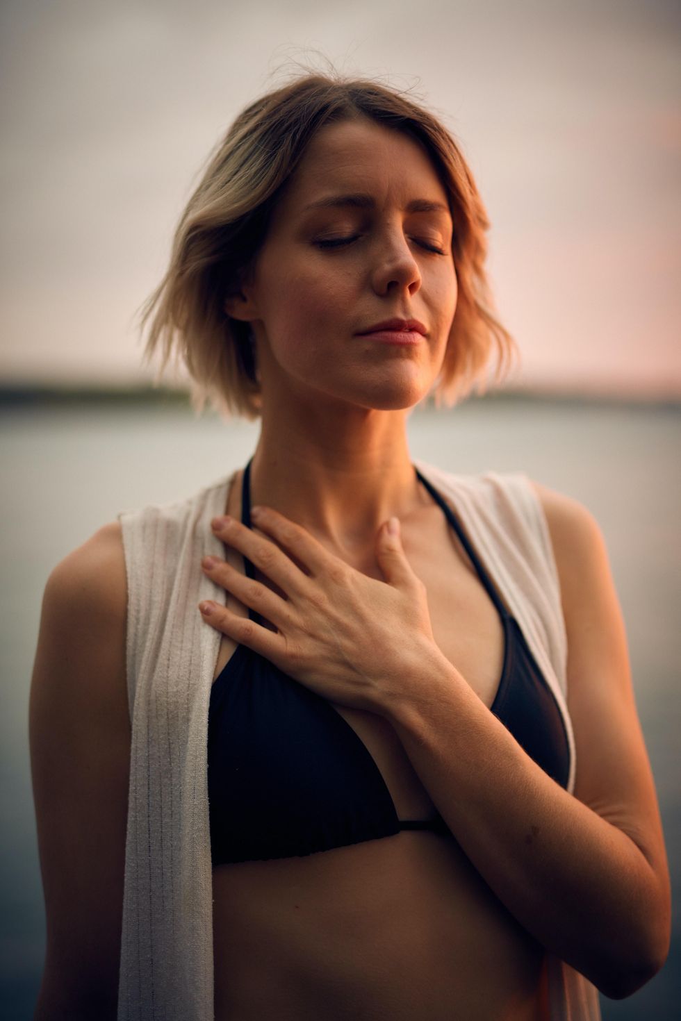 A woman meditating, with hand on heart.