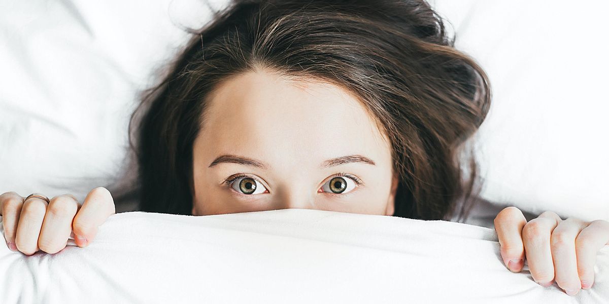 young woman covering her face with blanket