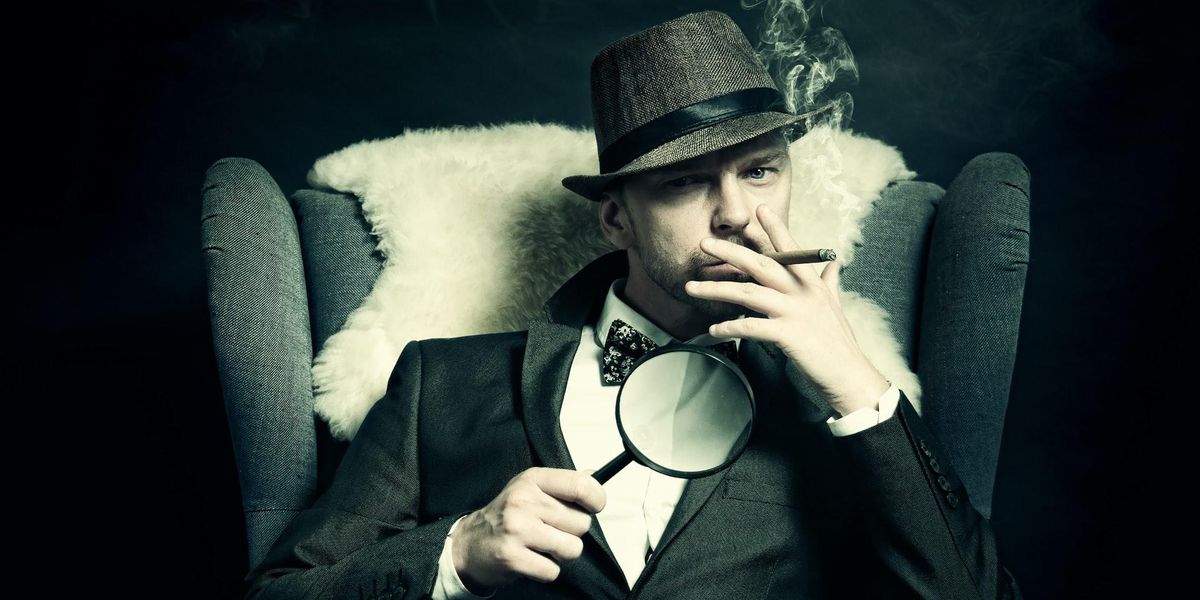 A man sits in a chair with a magnifying glass while smoking a cigarette