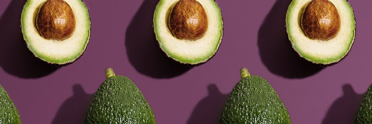 avocados cut in half are lined up with their seed still in the middle 