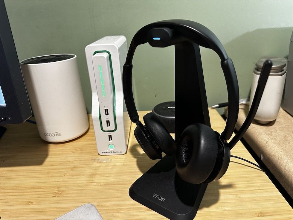 a photo of EPOS IMPACT 1061T ANC Headset and stand on a desk plugged in.