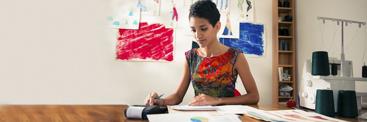 a woman at a desk with a calculator and sketches behind her