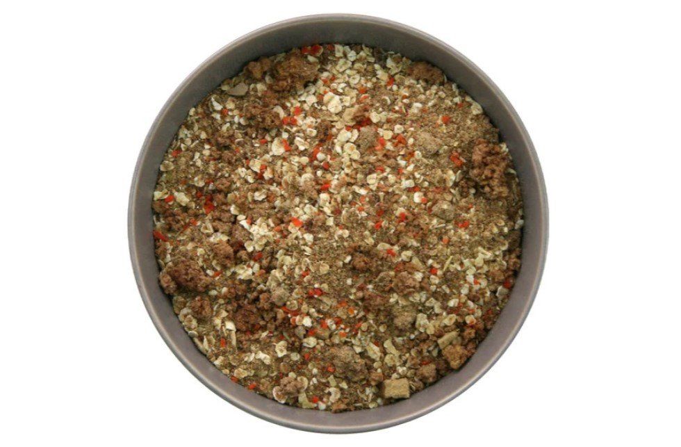 Dry pet food with grains and dried vegetables in a round bowl.