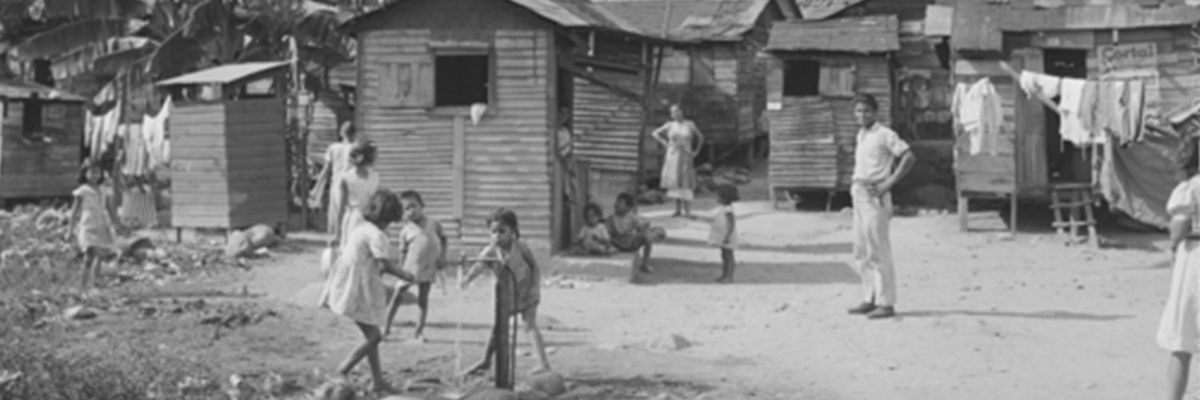 a black and white photograph of a village in Puerto Rico with kids playing and adults watching over them