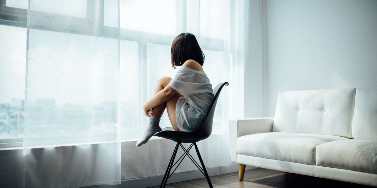 woman sitting on black chair in front of window with white curtains