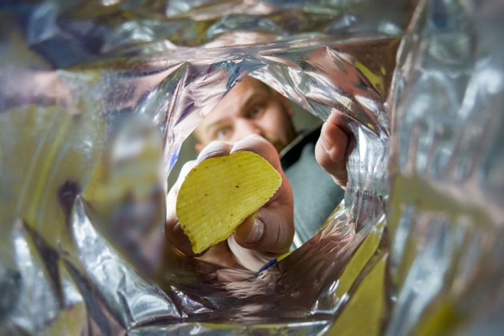 man pulling chip out of a chip bag