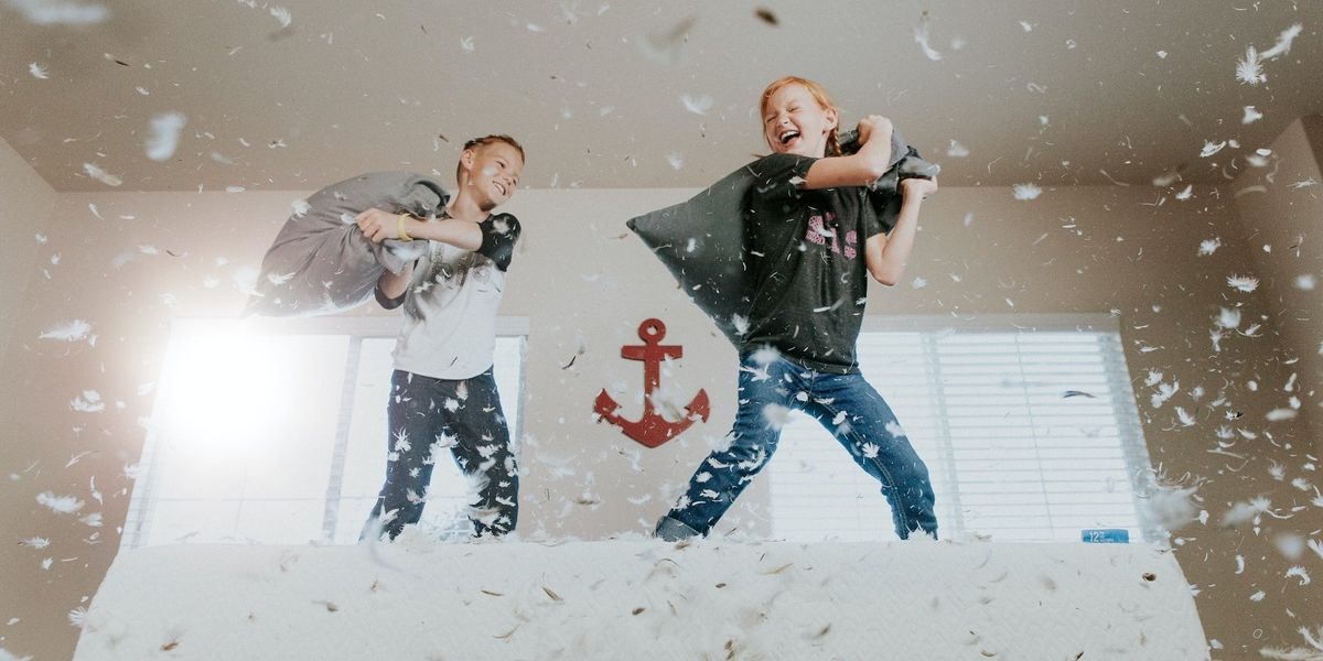 Two young boys are having a pillow fight