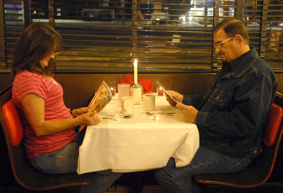 A couple look at a Waffle House menu illuminated by candlelight on Valentine's Day.