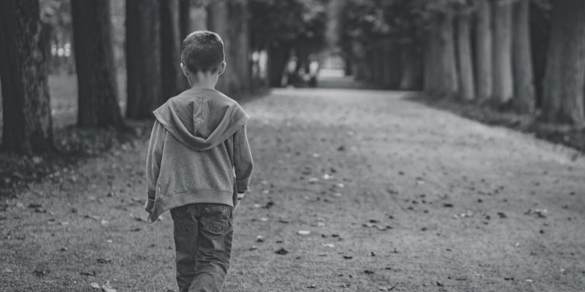 Little boy walking alone down the road