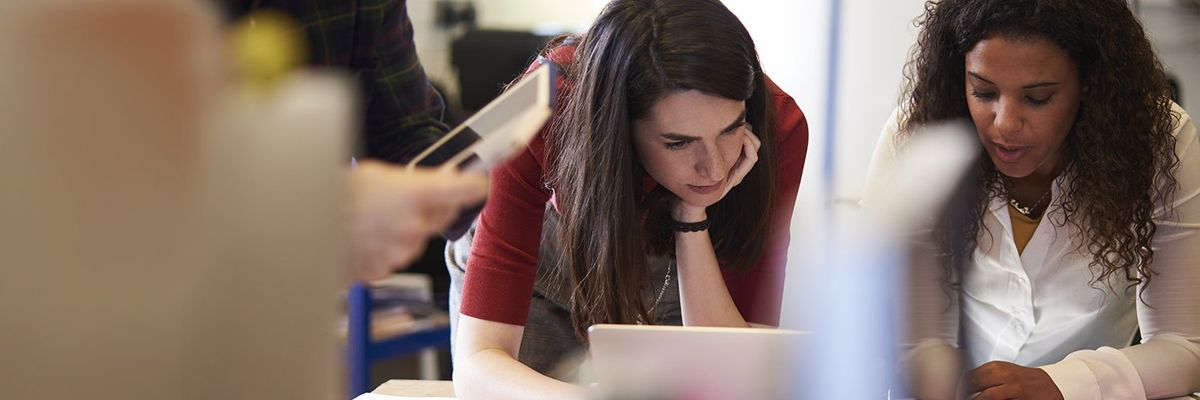 two women working while looking at a laptop