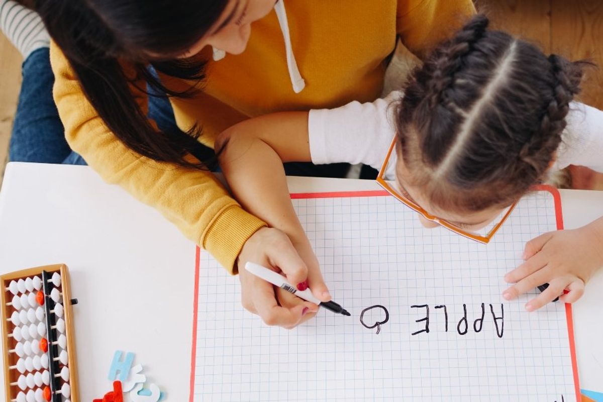 mom helping her daughter draw an apple