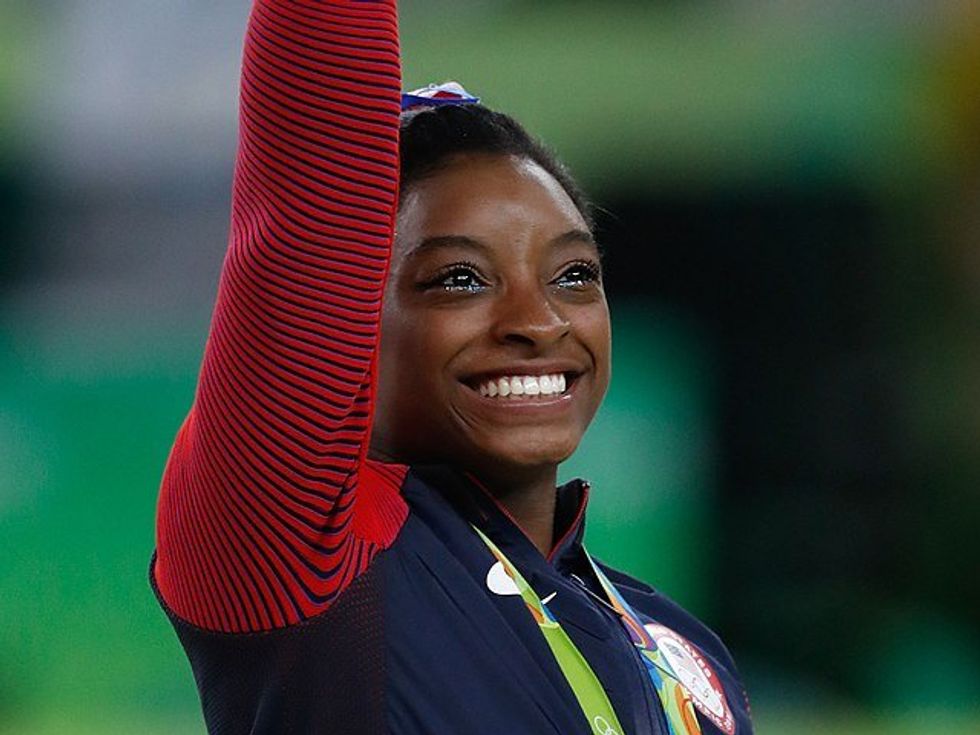 simone biles smiling and waving from the podium