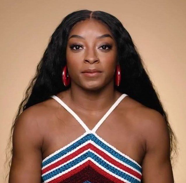 Simone Biles with her hair down looking directly at the camera