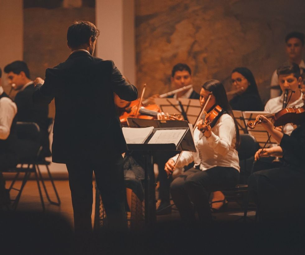 A music conductor leads a small orchestra.