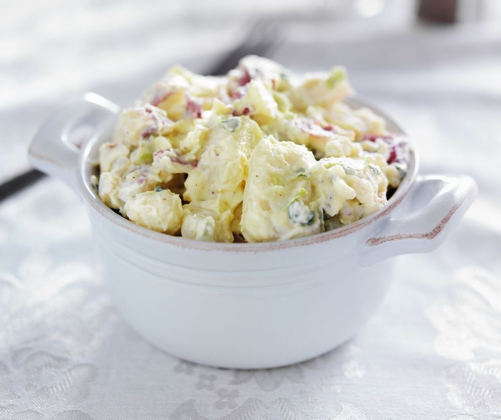 A small white ceramic pot filled to the brim with potato salad