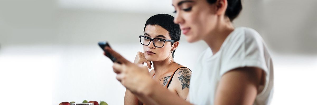 a girl giving the side eye to another girl that's on her phone