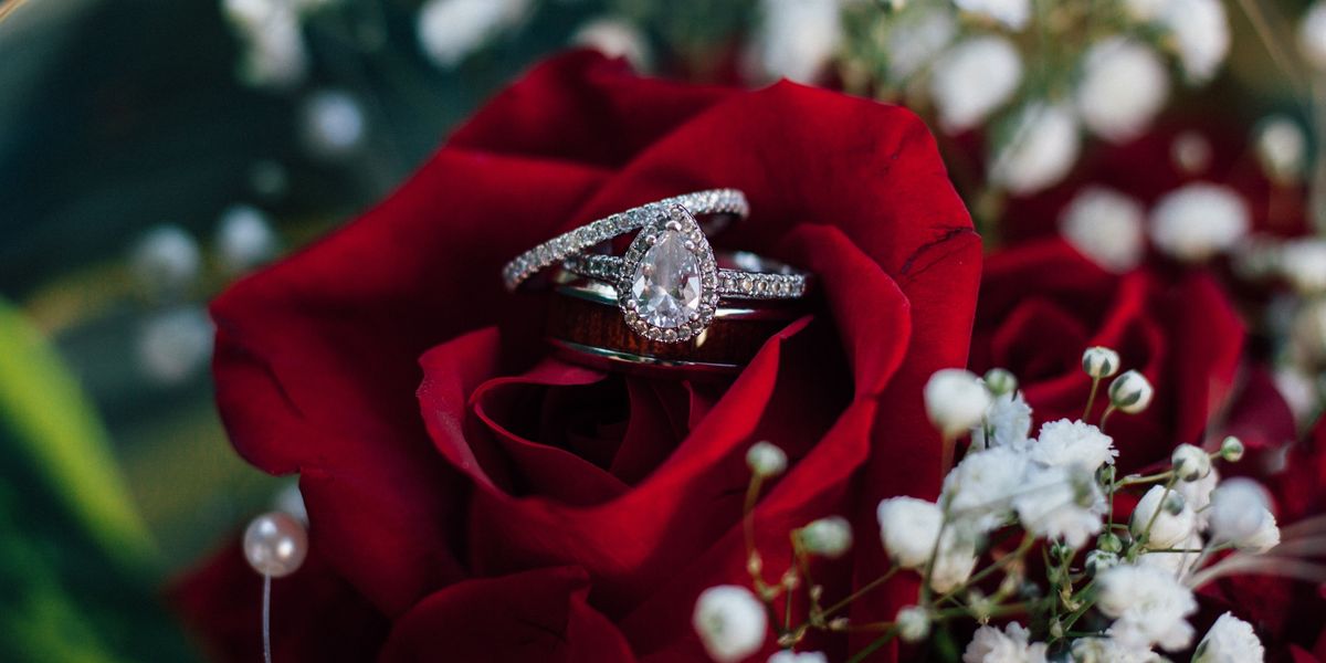 Engagement ring on top of red rose