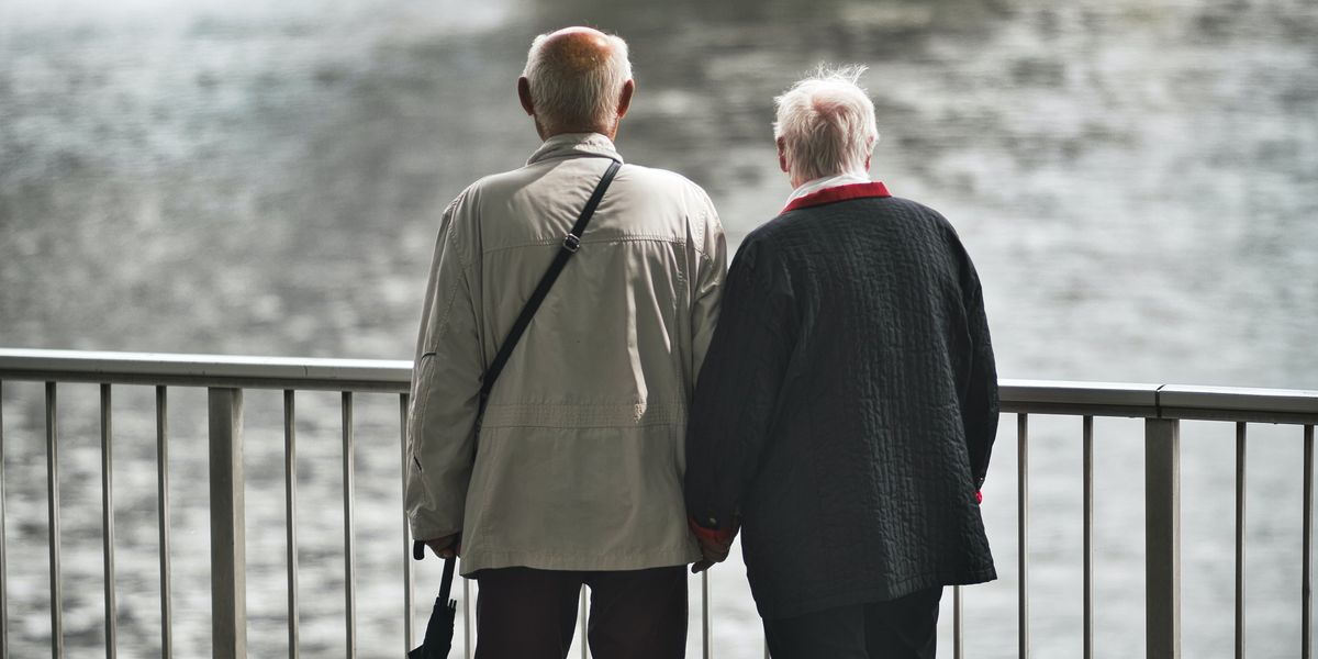 Two elderly people looking at the river from a bridge