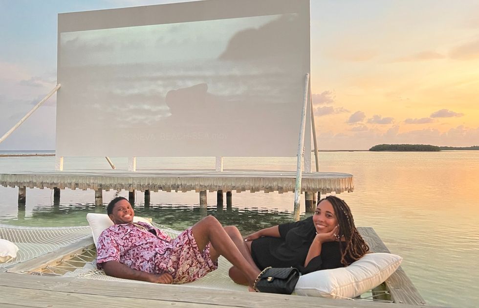 couple-relaxing-in-the-ocean-lounging-on-a-hammock-watching-a-movie-on-a-projector