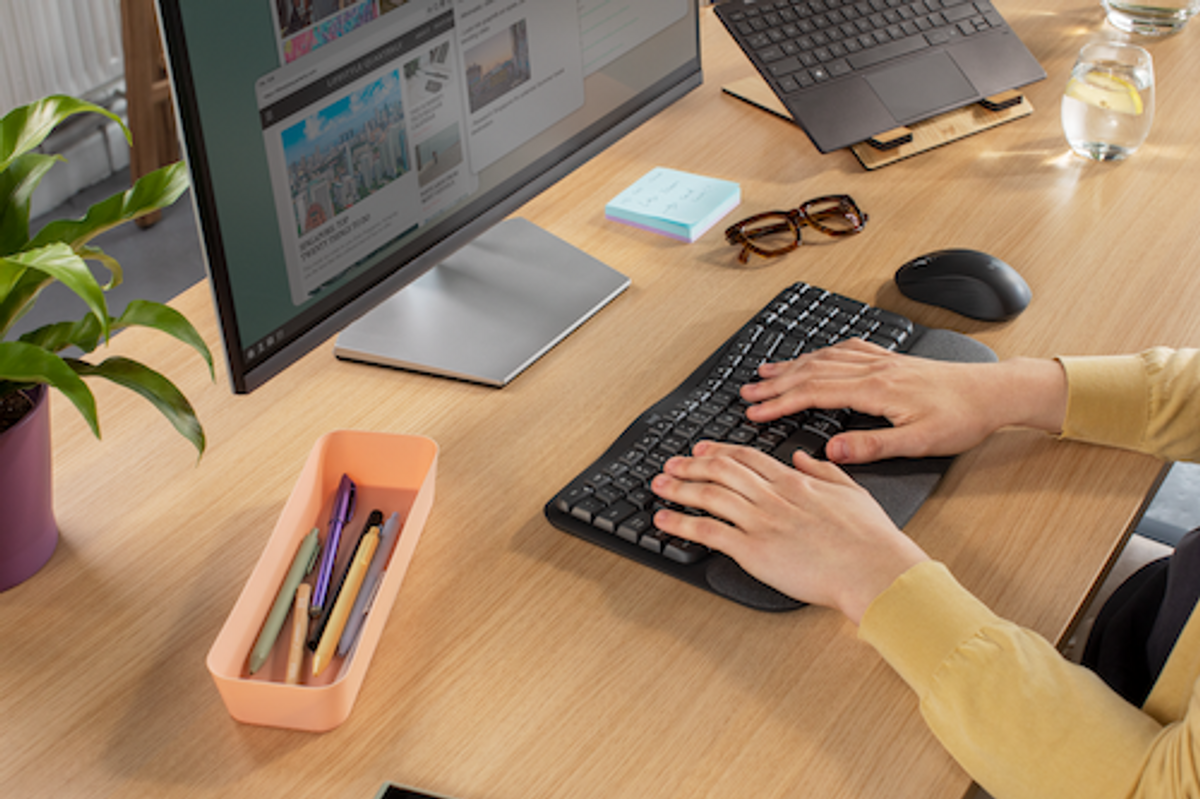 a photo of a woman's hands typing on a Logitech Wave Keys