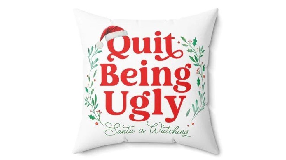 A white throw pillow that says, "Quit Being Ugly: Santa is Watching."