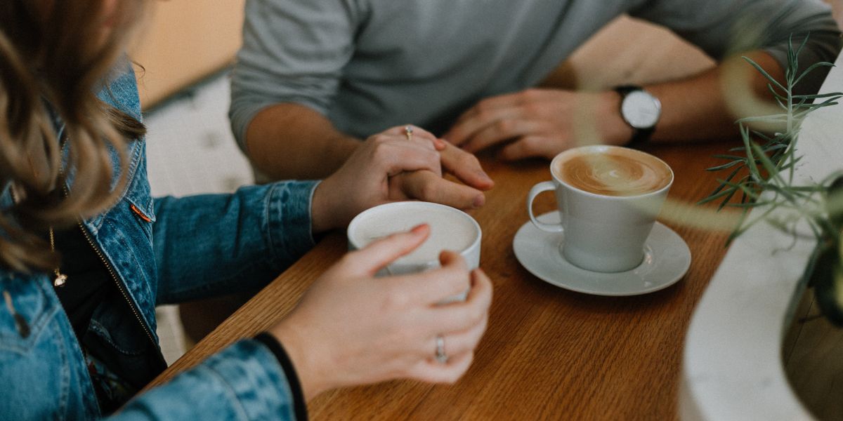 woman touchig man's hand at coffee date