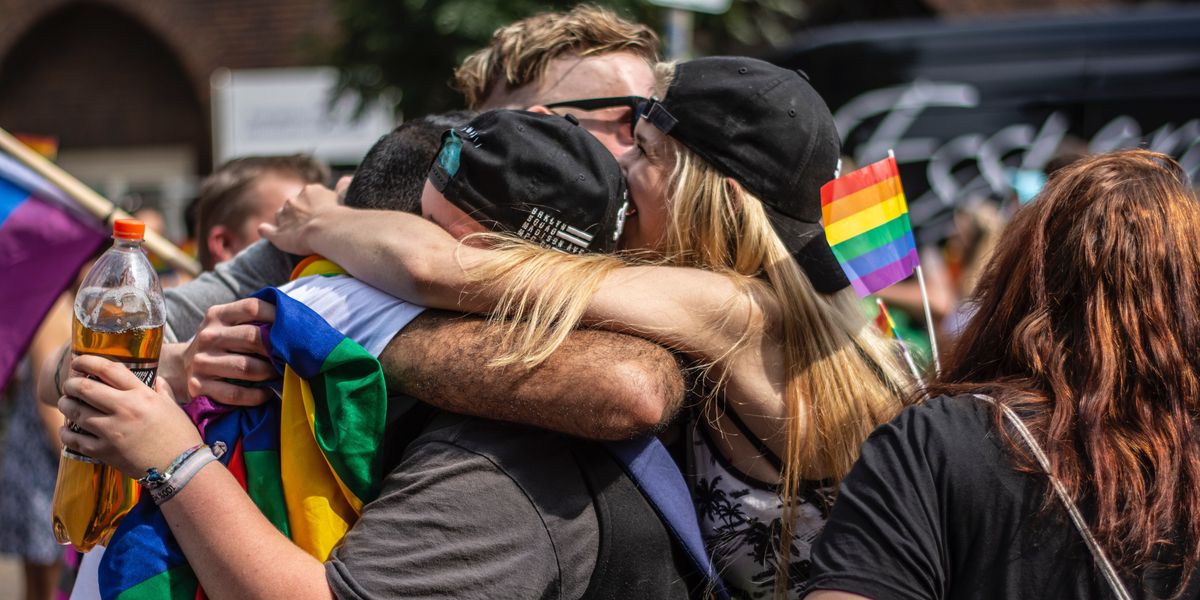 Group hug with people holding rainbow flags