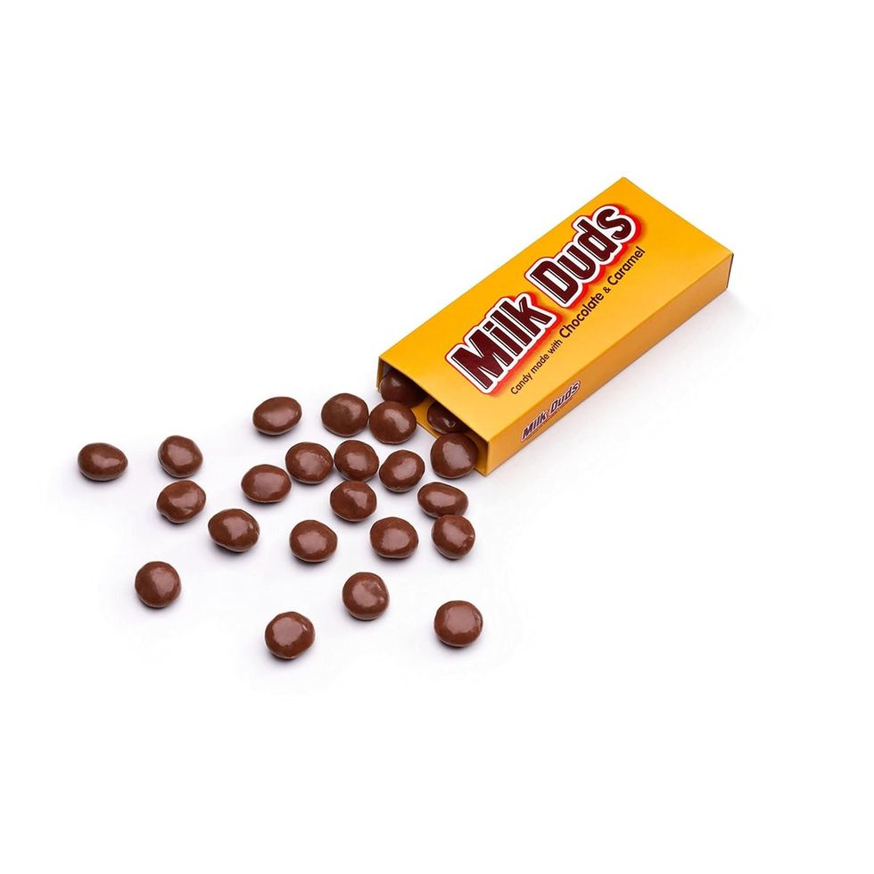 A box of Milk Duds with several of the chocolate candies spilling out.