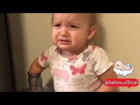 baby with her arm in the top of a water bottle