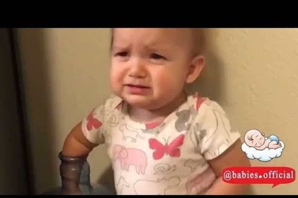 baby with her arm in the top of a water bottle