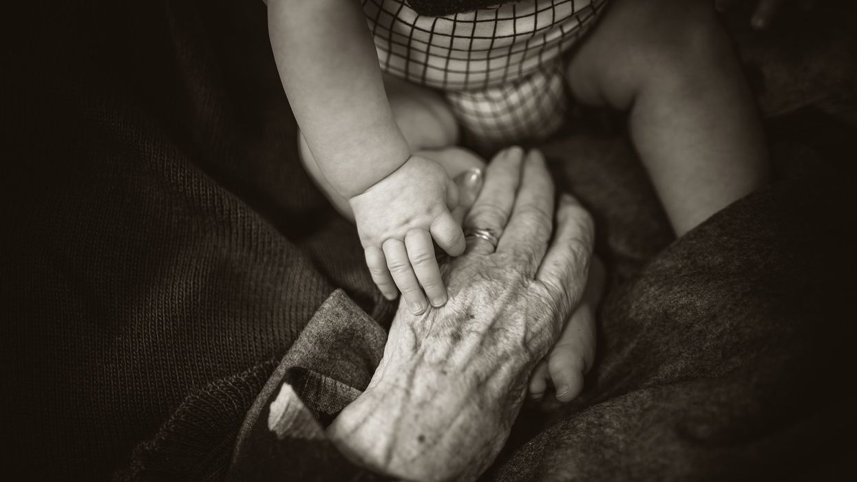 A baby's hand holds an elderly woman's hand